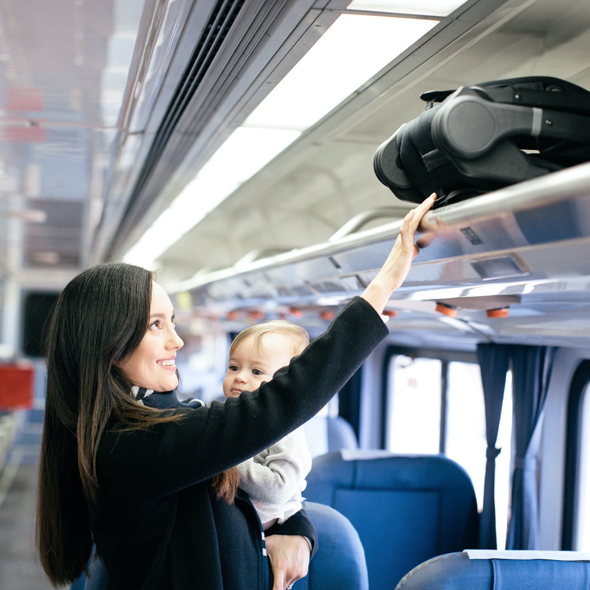 lady holding baby and pushing stroller into overhead compartment