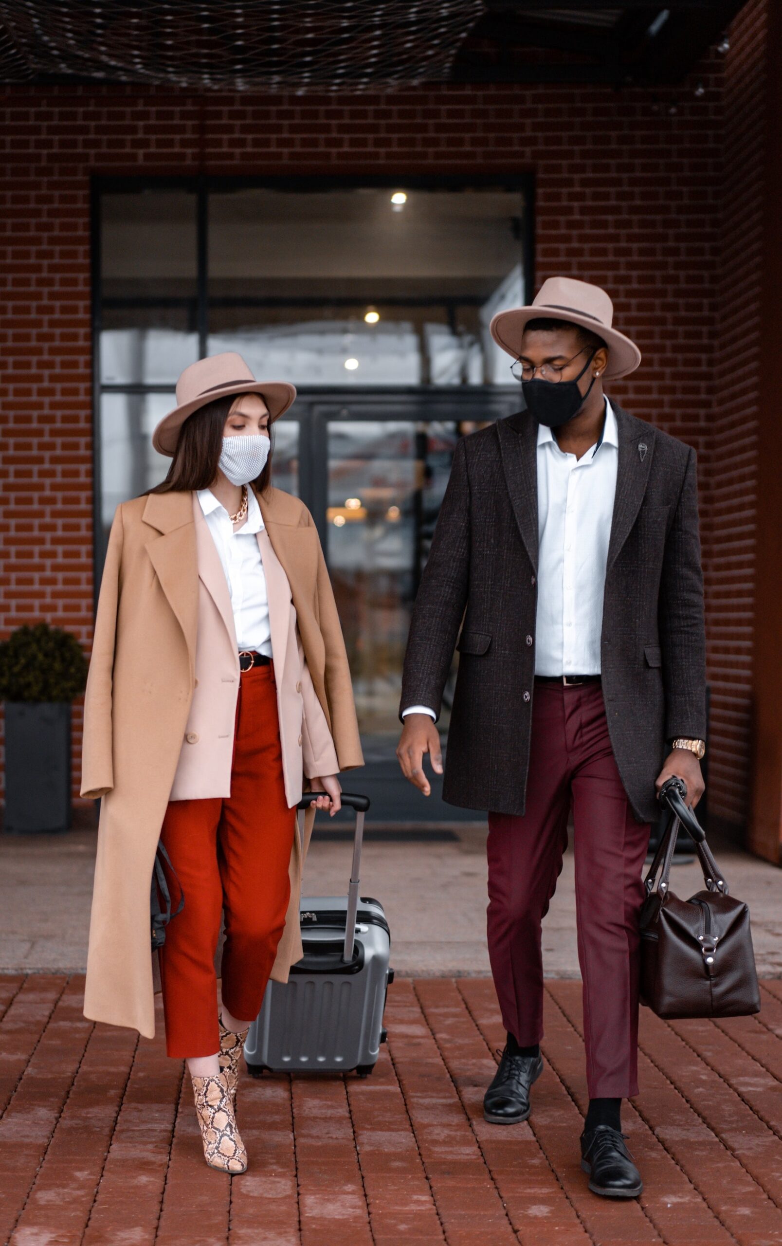 man and woman wearing masks and holding different types of luggage