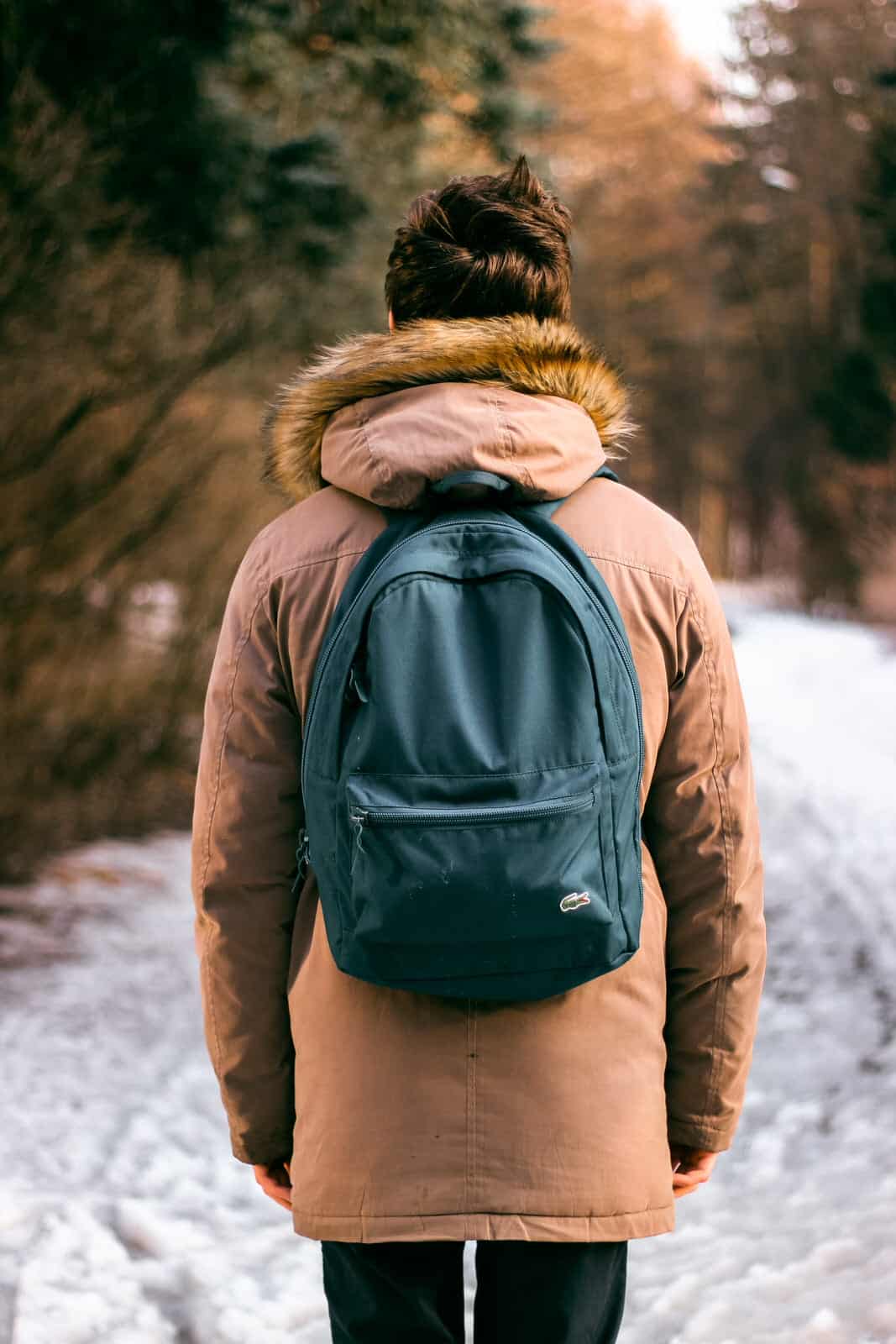 girl walking through snow with green polyester backpack on