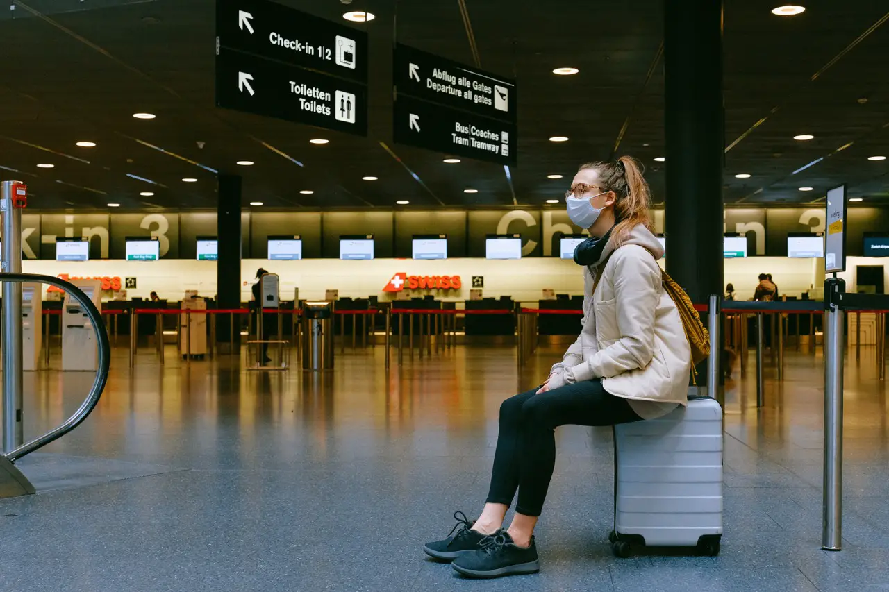 woman sitting at airport waiting for delayed luggage