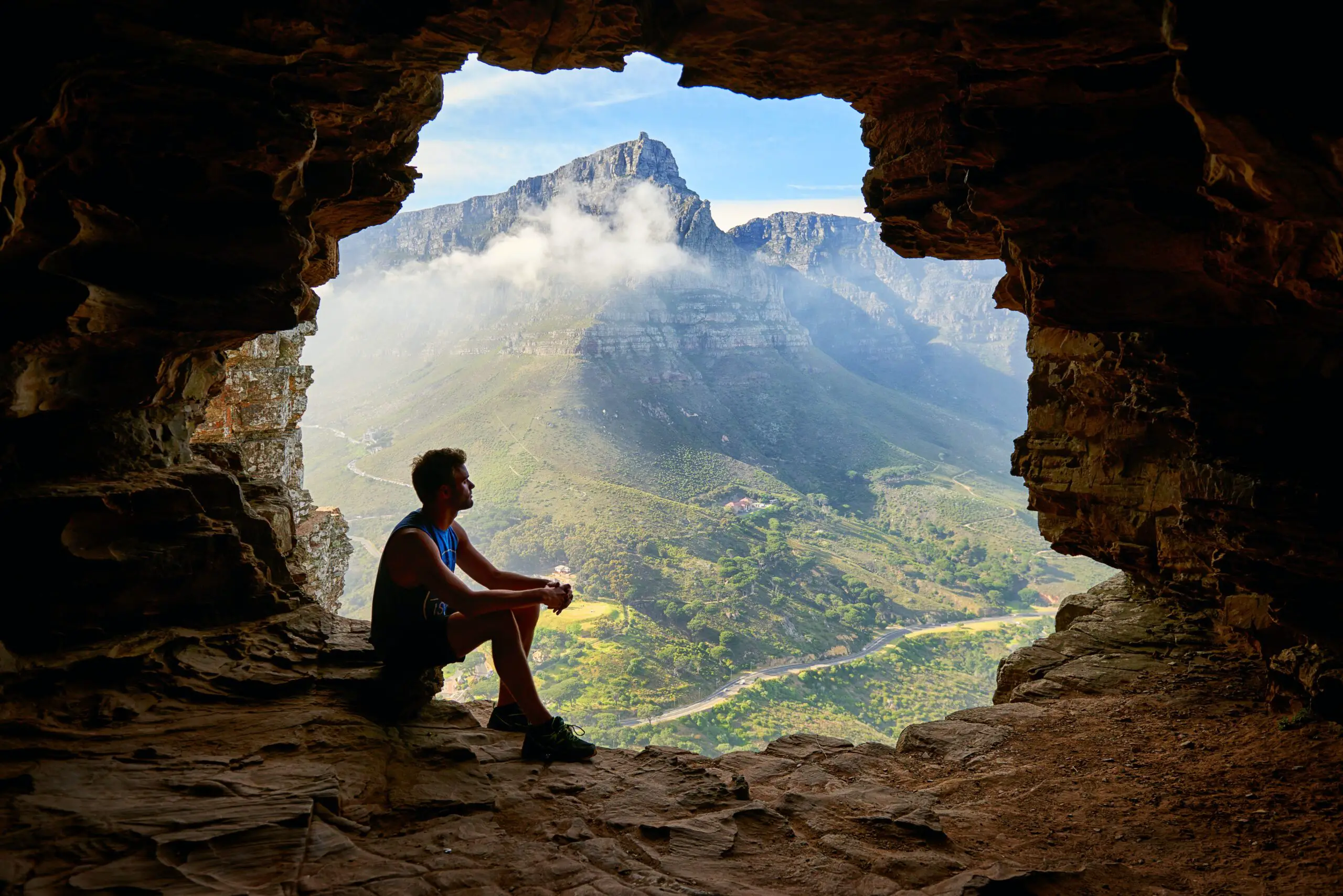 man posing near opening of cave while traveling solo