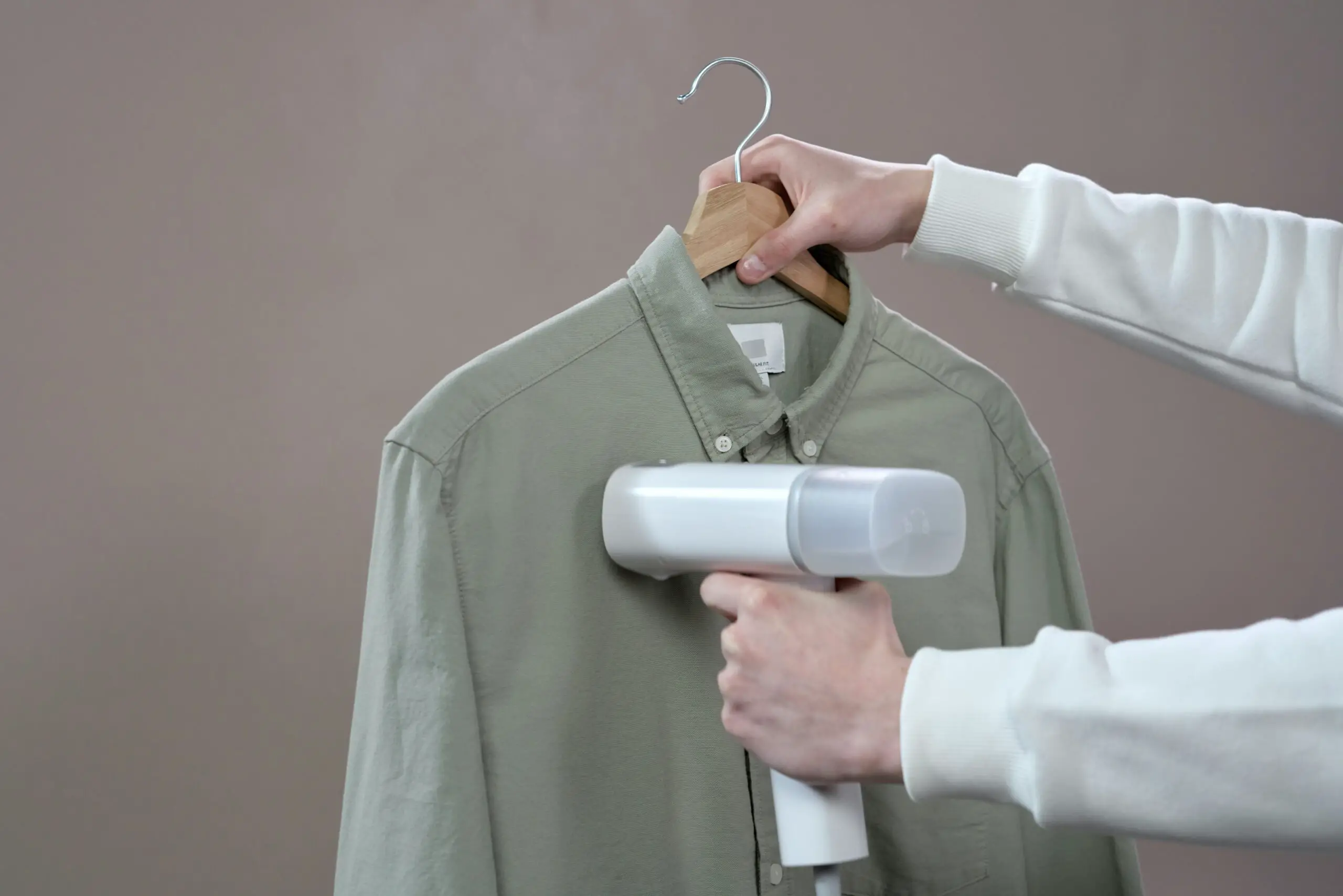 Clothes steamer being used by guy on clothes