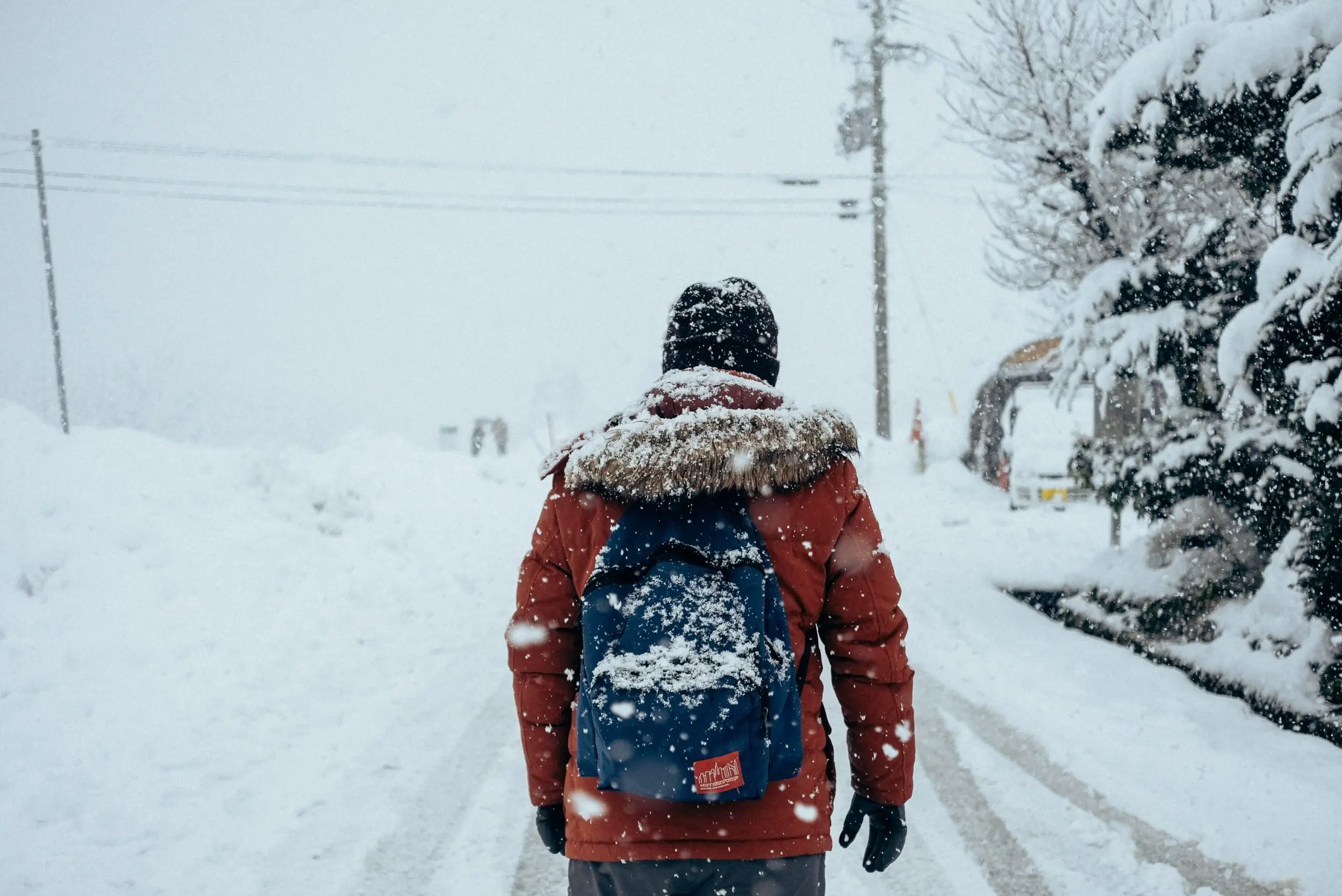 Man walking through snow while traveling with simple backpack