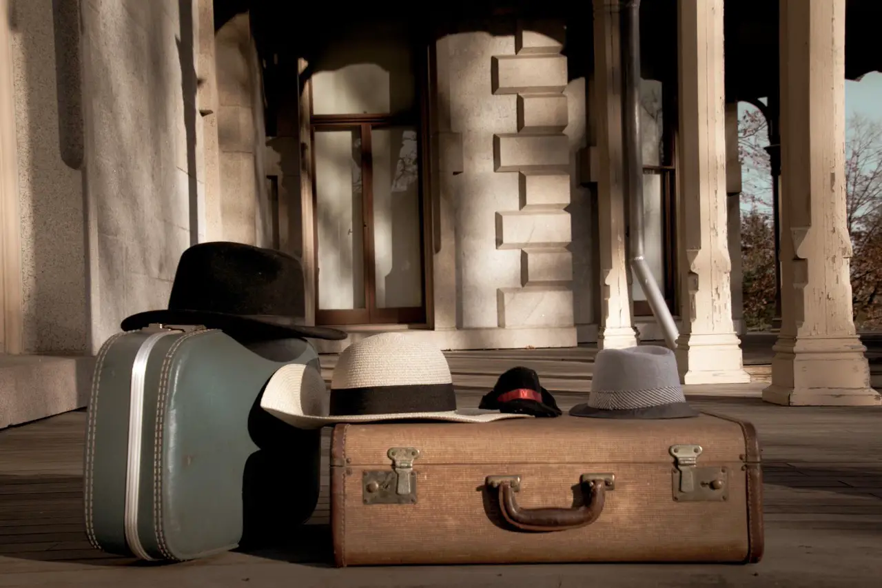 antique looking luggage laying on ground with hat on top