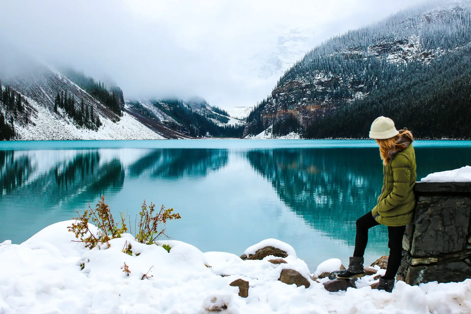 woman hiking through snow next to lake