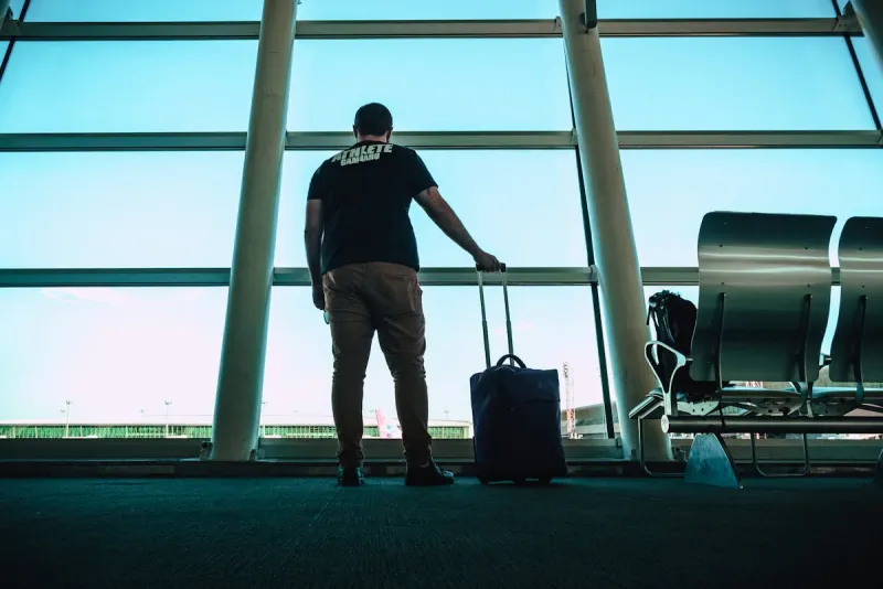 Man holding luggage bag while shopping for affordable suitcases