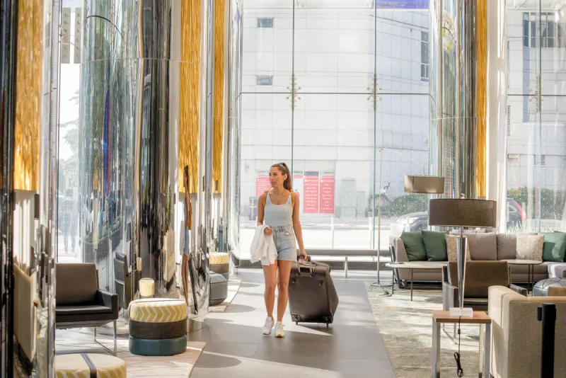 Traveler pulling hardside carry-on suitcase through airport terminal