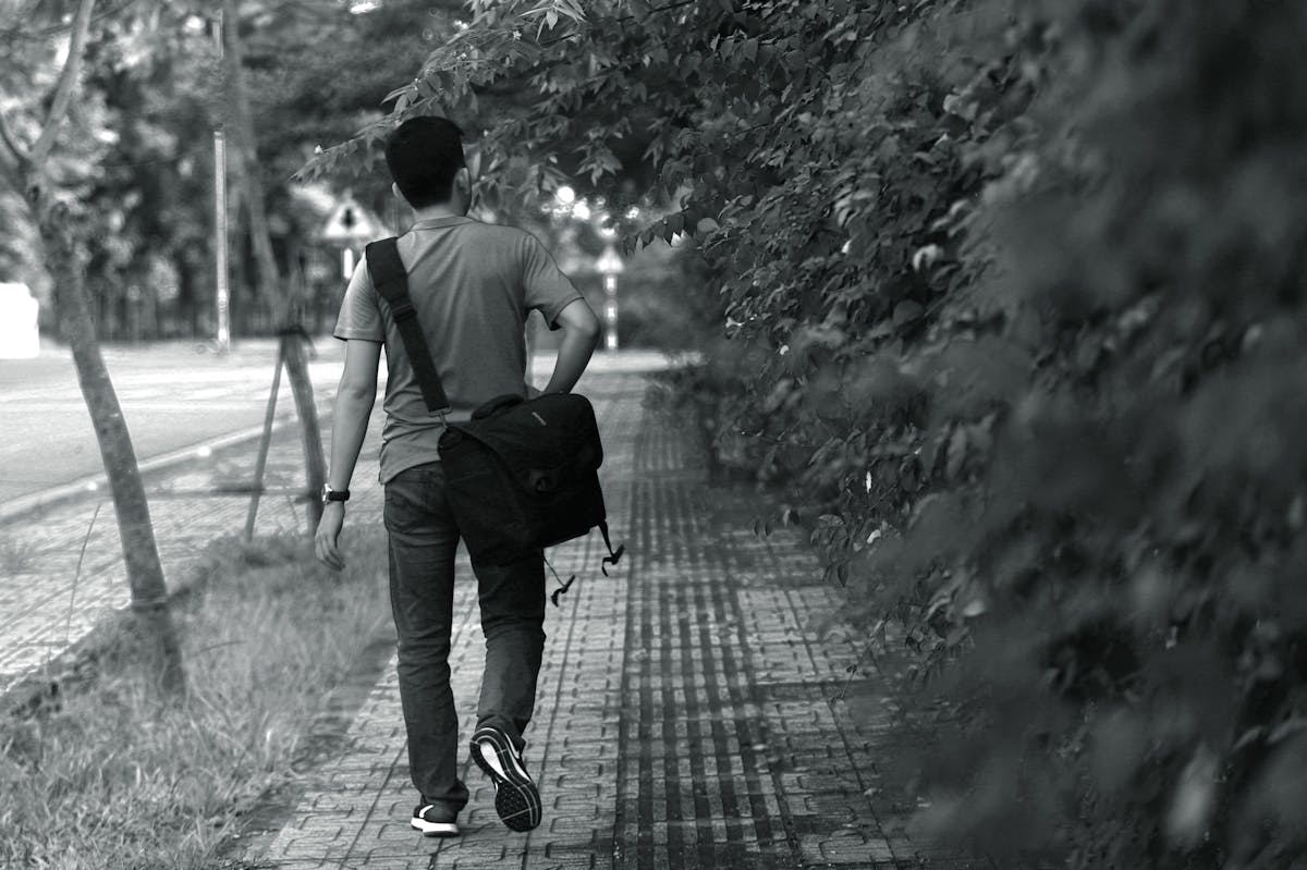 Man wearing a crossbody sling bag while walking in an urban setting