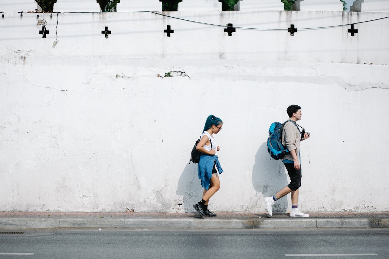 Young adults with crossbody bags walking along a city sidewalk