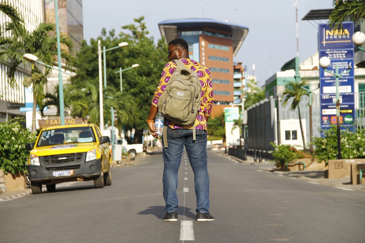 Man standing on an urban street enjoying the cityscape with a sling bag