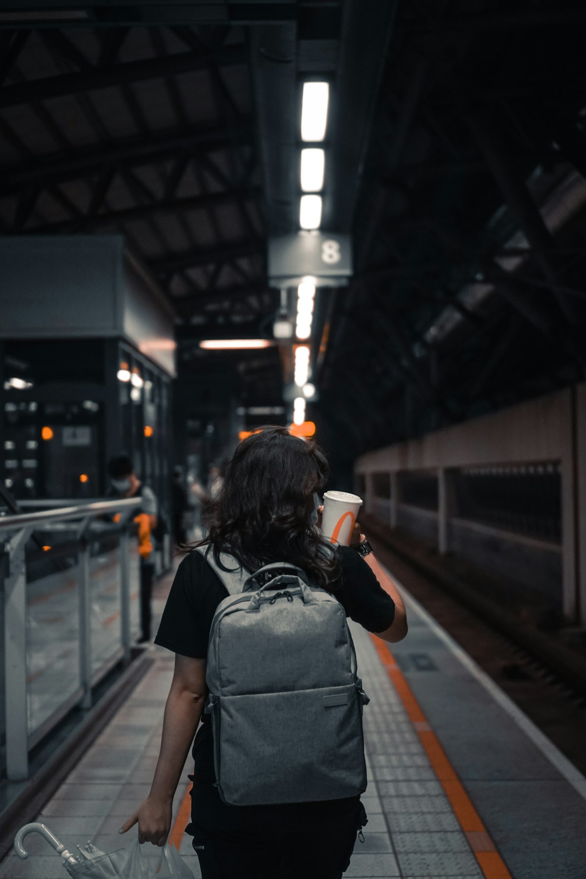 Woman wearing a compact gray backpack while walking through a train station platform