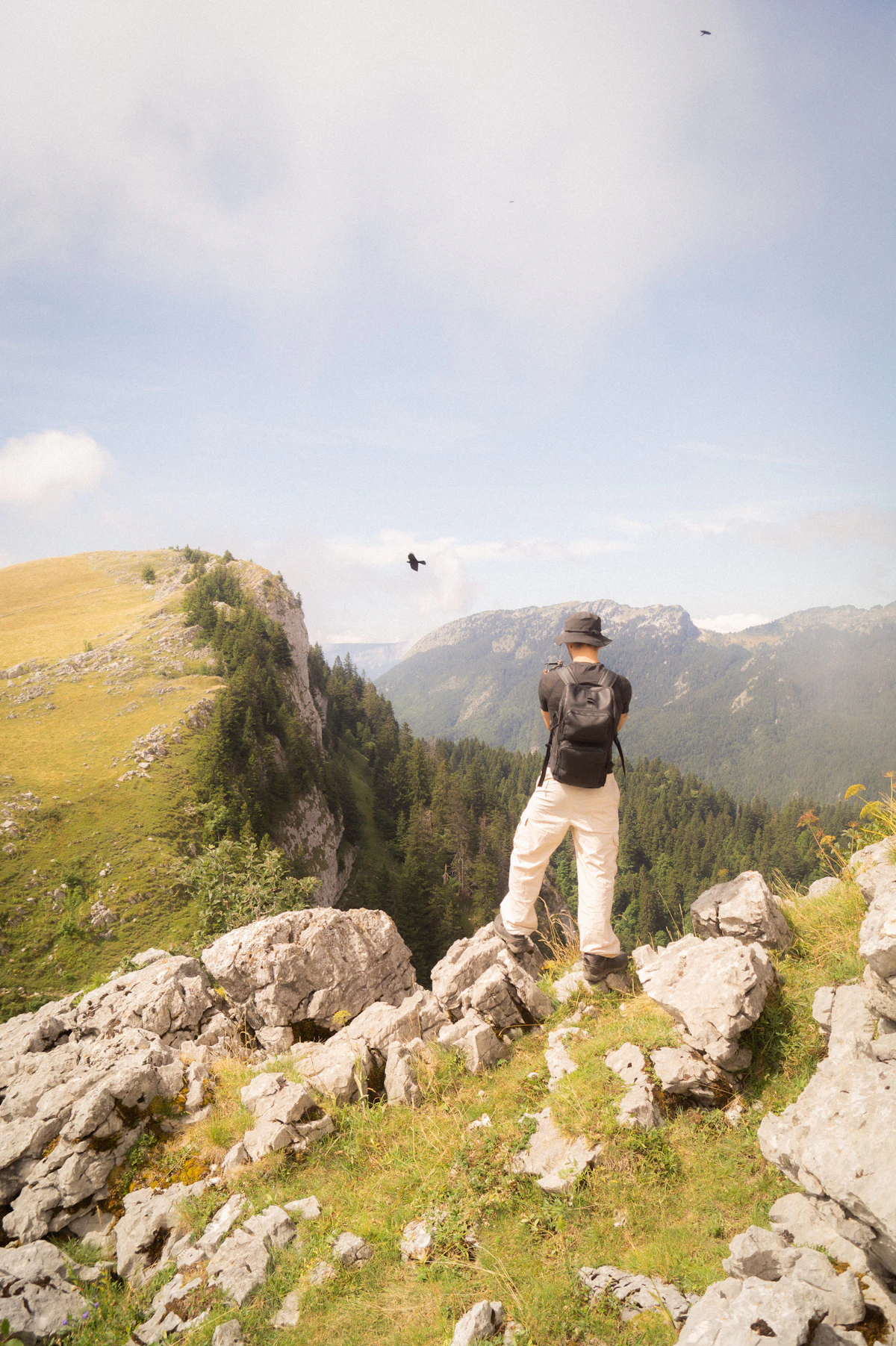 Hiker wearing a daypack standing at a scenic mountain overlook with expansive valley views