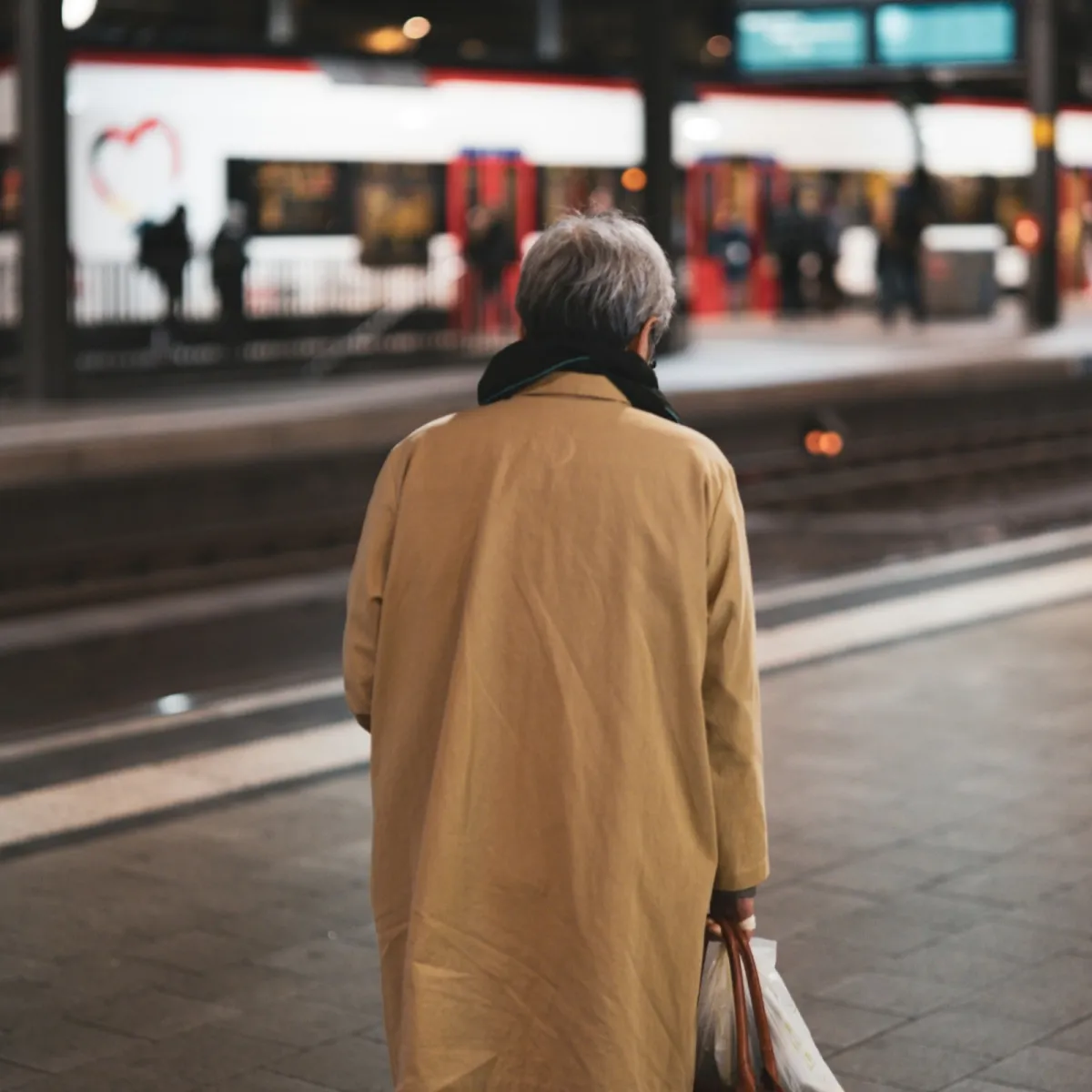 Solo traveler with a backpack waiting on a train platform, a common target environment for anti-theft bag features.