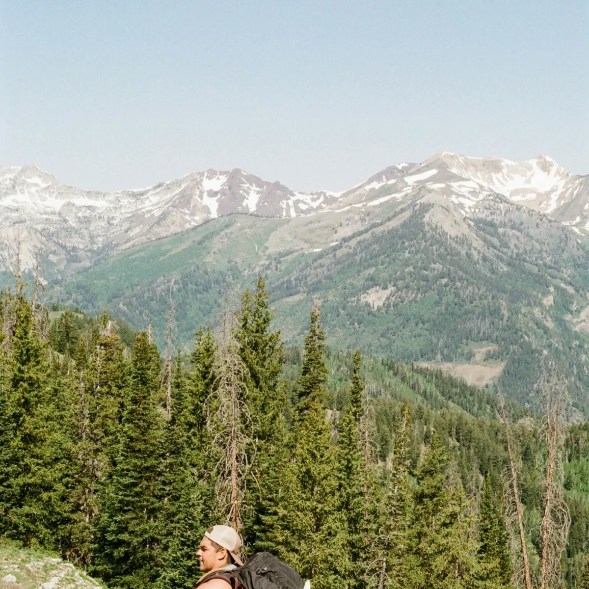 Hiker standing at a mountain overlook with a loaded backpack, illustrating upright posture on the trail