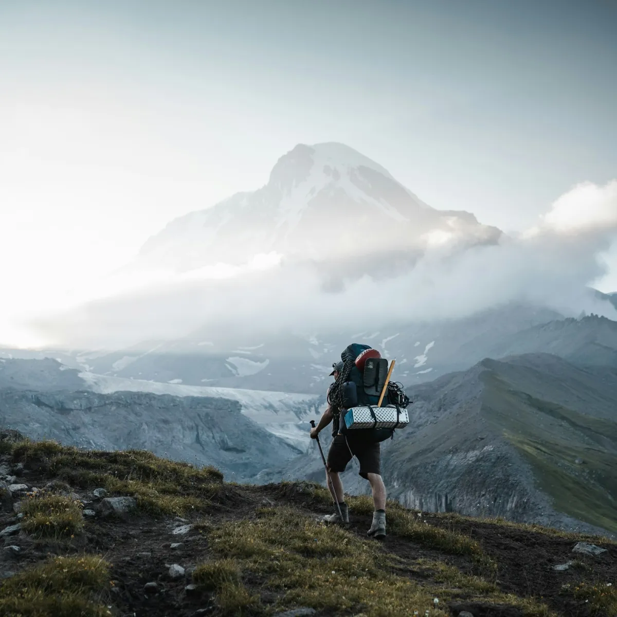 Man hiking uphill with a full backpack, showing how load distribution affects back comfort on a long climb