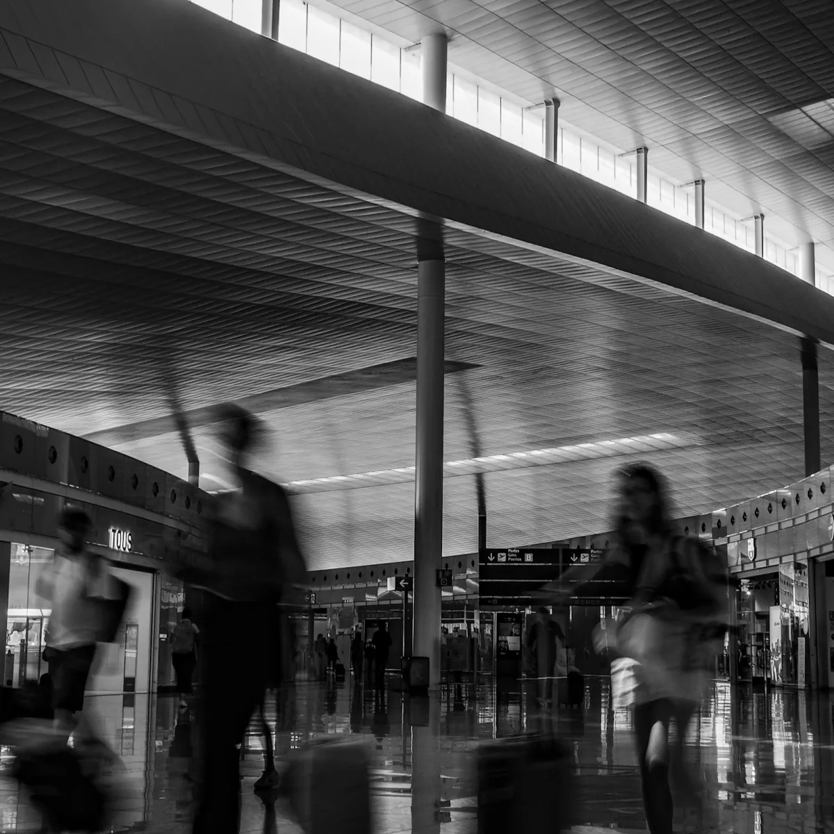 Travelers with luggage walking through a bright, blurred airport terminal on their way to a gate