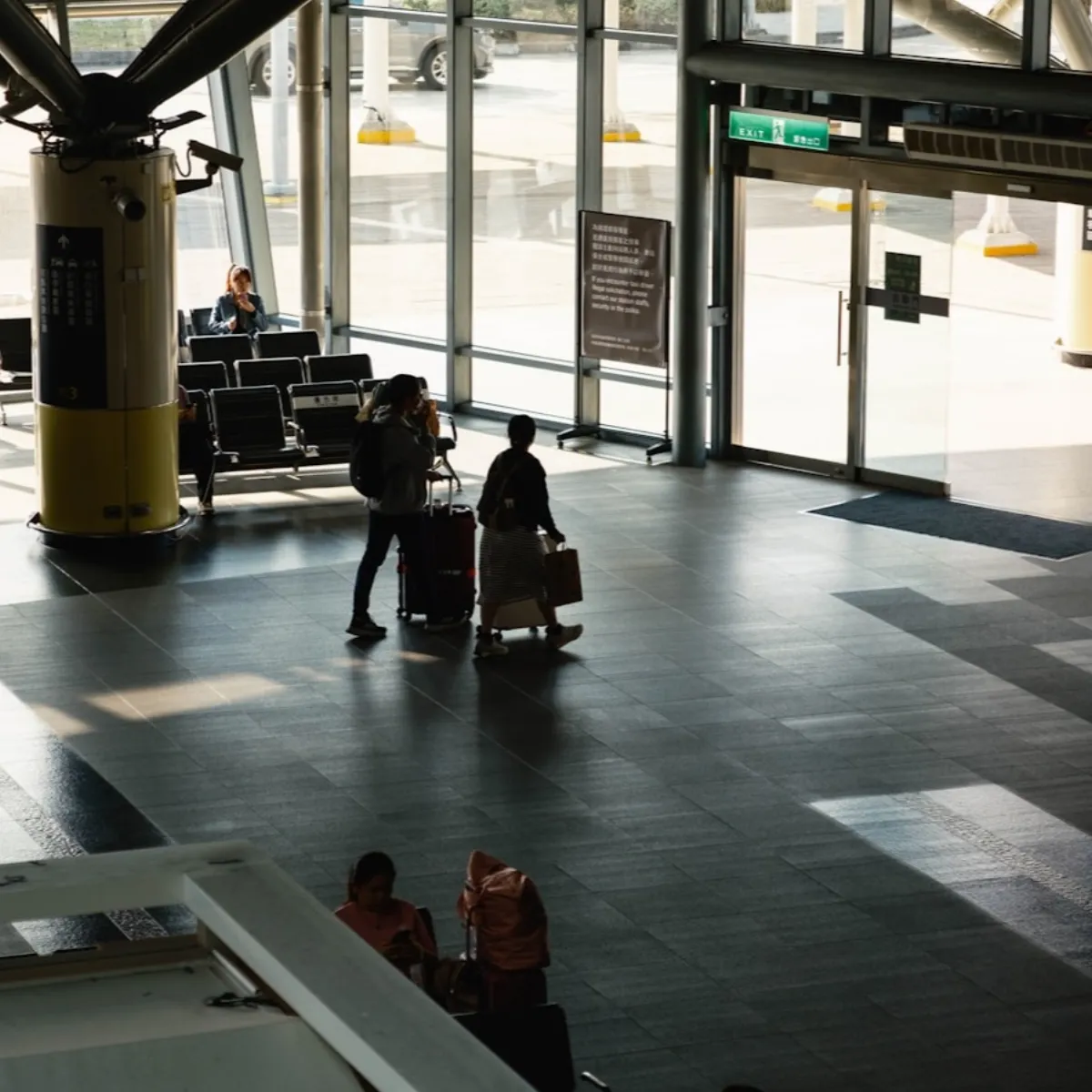 People waiting with carry-on luggage in a bright modern airport terminal near the boarding gates