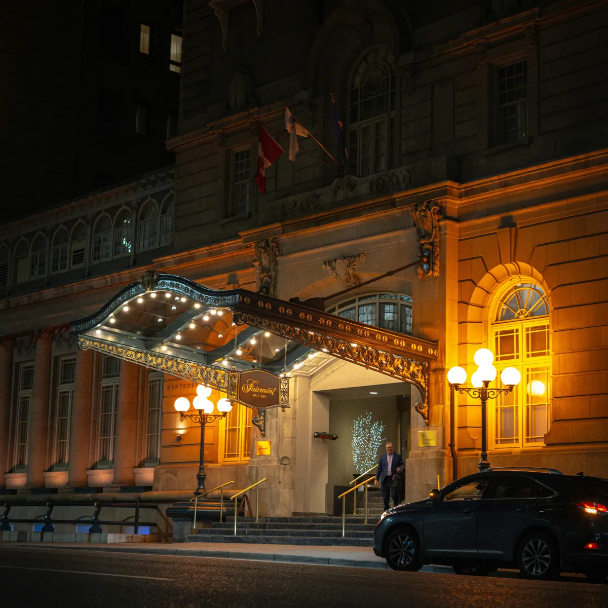 Illuminated hotel entrance at night with a car pulled up for a late arrival