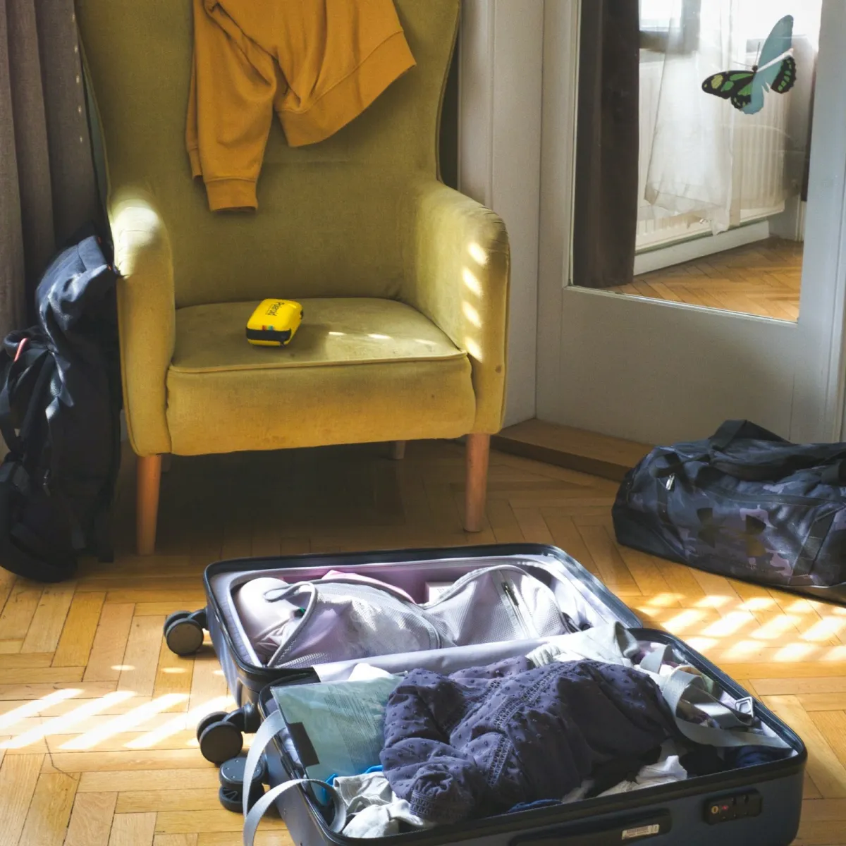 A neatly organized open suitcase with folded clothes arranged in flat stacks alongside travel accessories to maximize packing efficiency