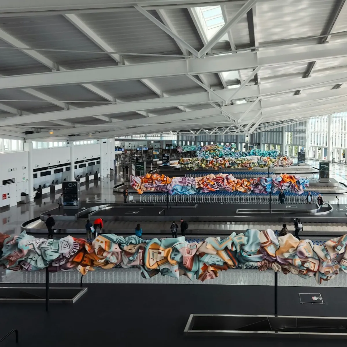 Travelers collecting suitcases from an airport baggage claim carousel where luggage damage and loss often surface