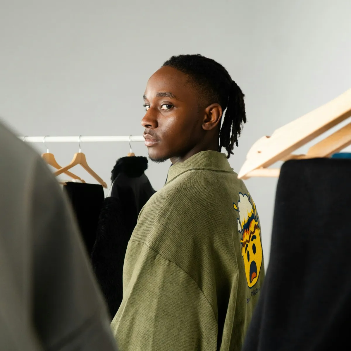 Young person in a graphic tee and urban layers, the streetwear silhouette Sprayground styles around