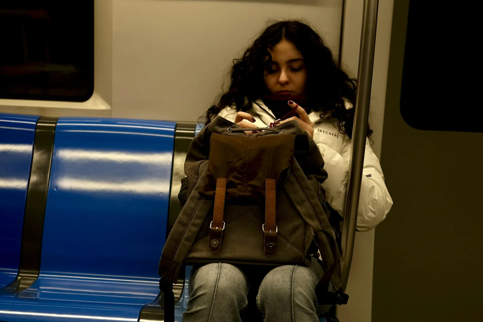Woman on a train looking in her backpack.