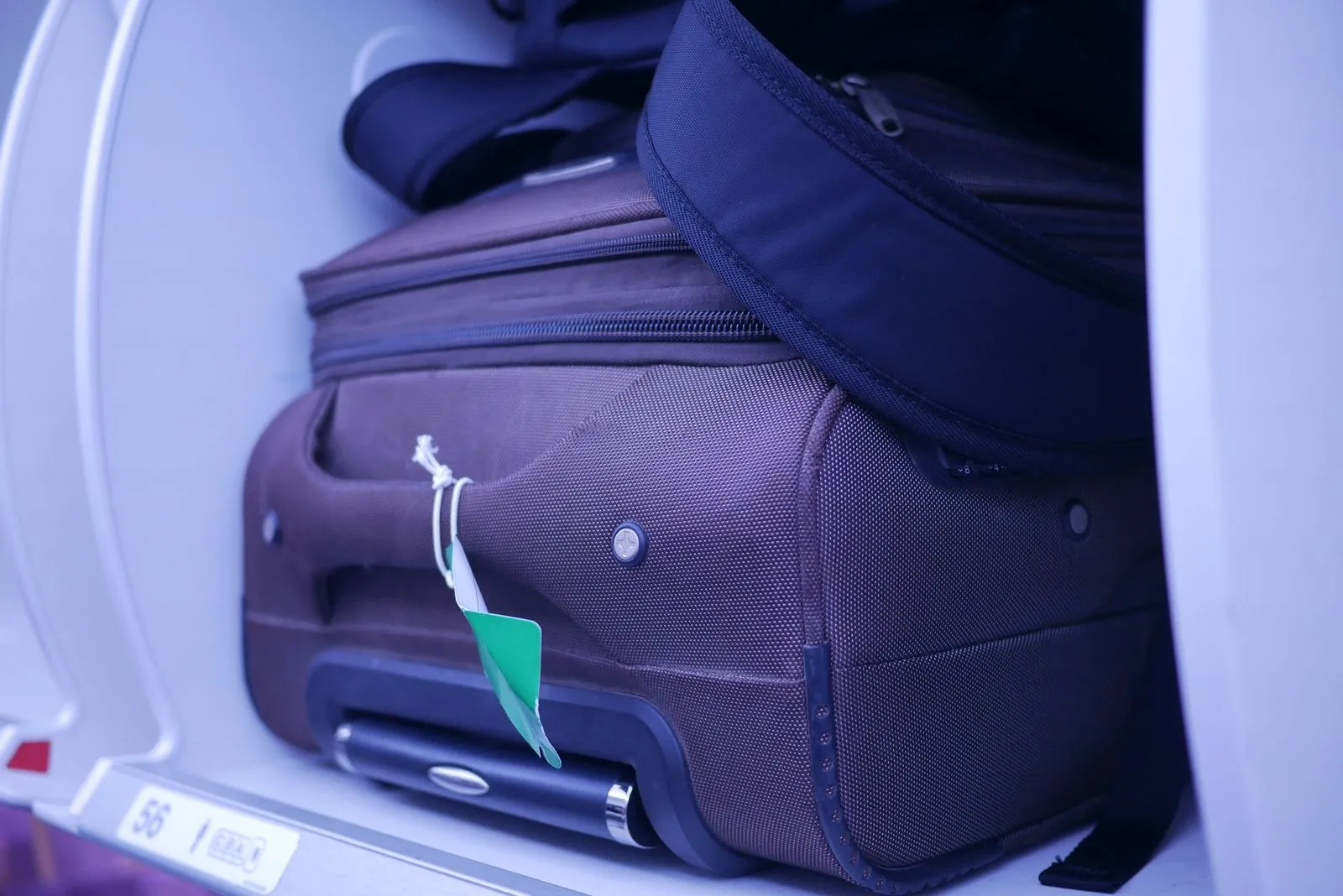 Carry-on suitcases packed into an airplane overhead bin