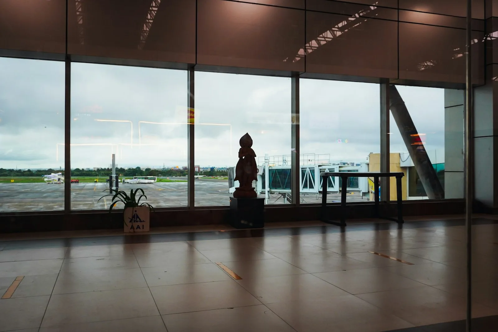 Travelers silhouetted in a modern airport terminal with glass windows and visible airplane tails.