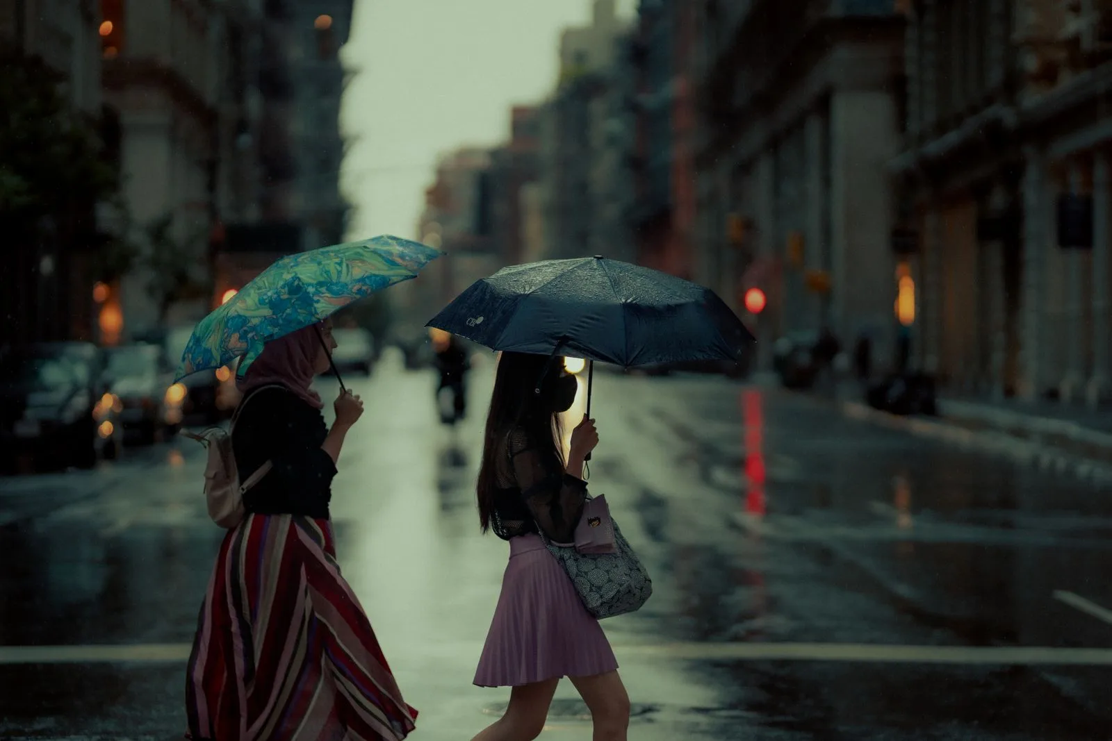 A rainy day in New York City with women crossing the street protected by umbrellas