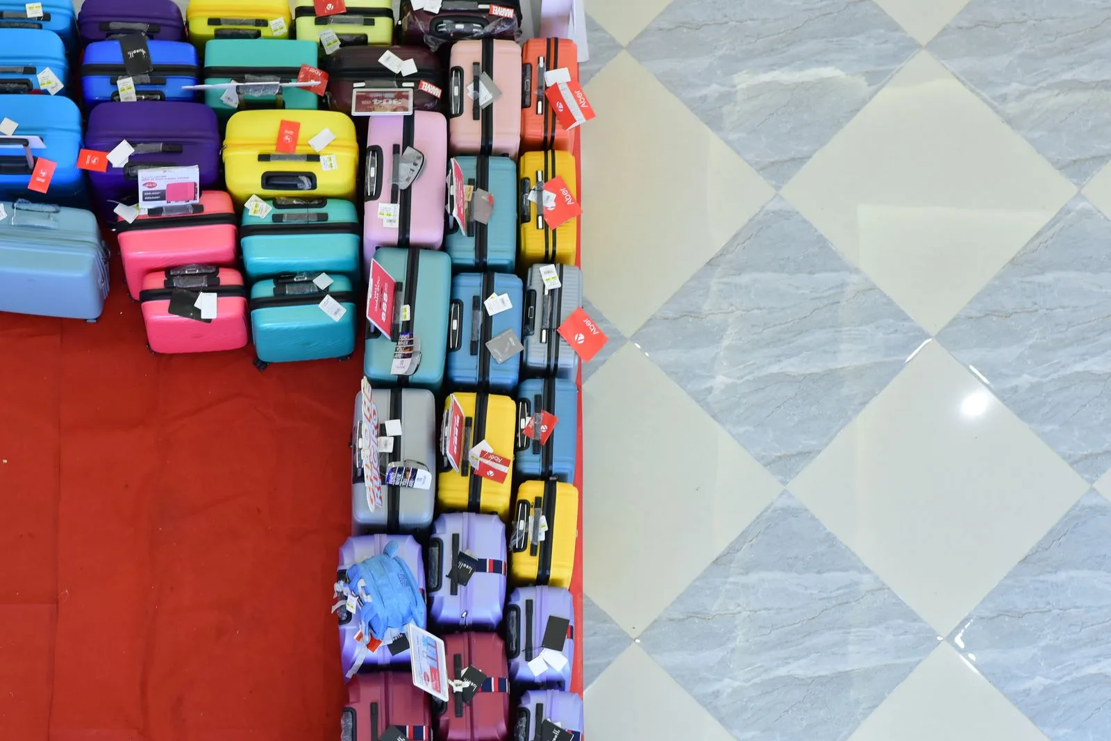 Top view of vibrant suitcases arranged on a checkered floor for sale