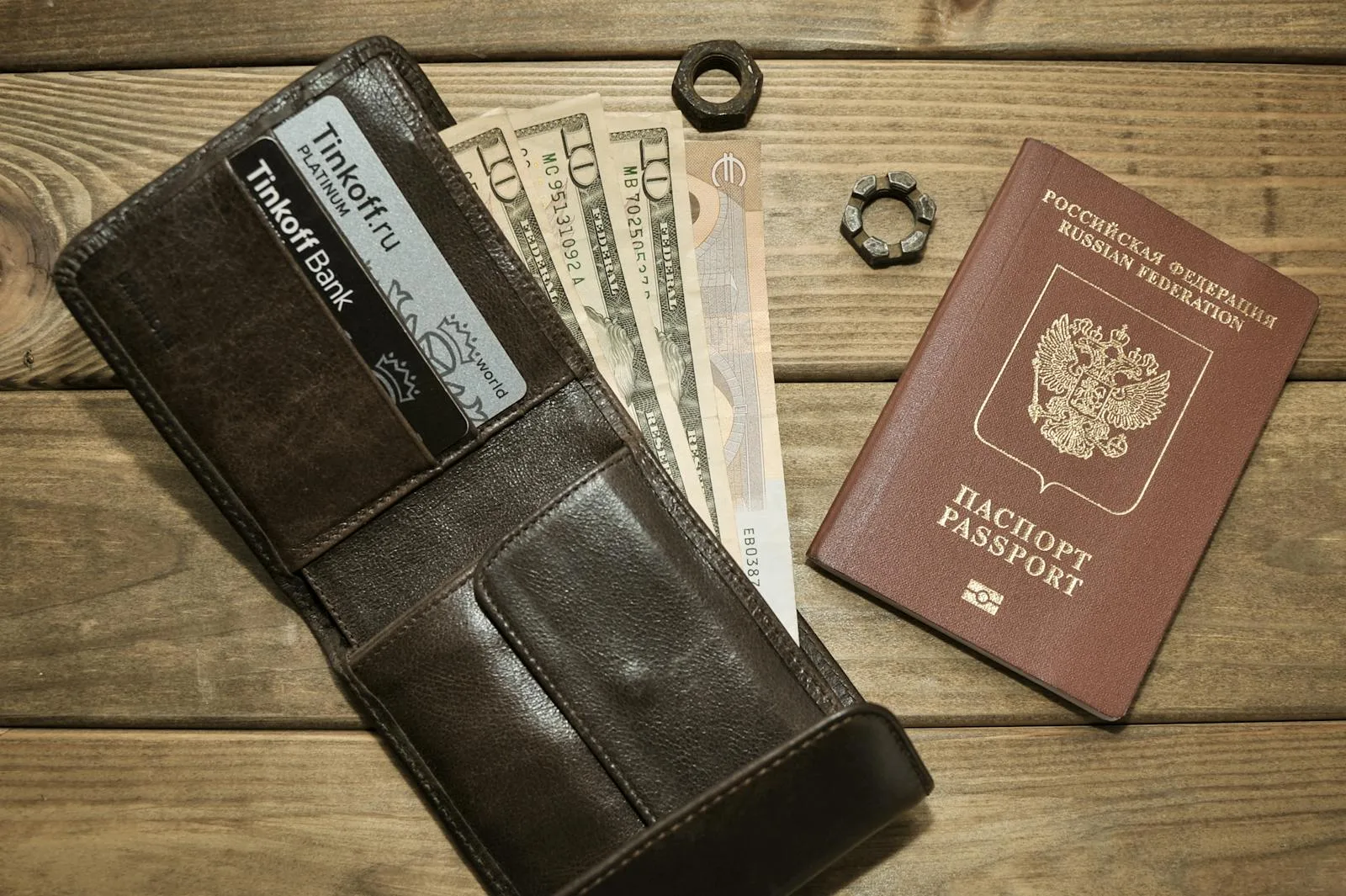Brown leather wallet with cards, assorted currencies, and passport on wood surface
