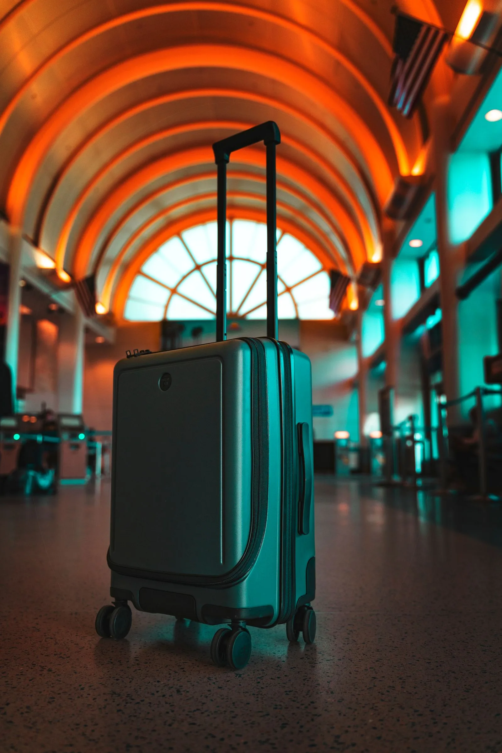 A modern suitcase in a vibrant airport terminal evokes travel excitement