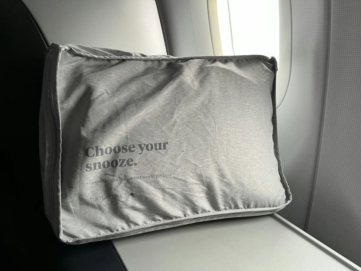 Soft grey airline sleep cushion left sitting on an empty economy seat