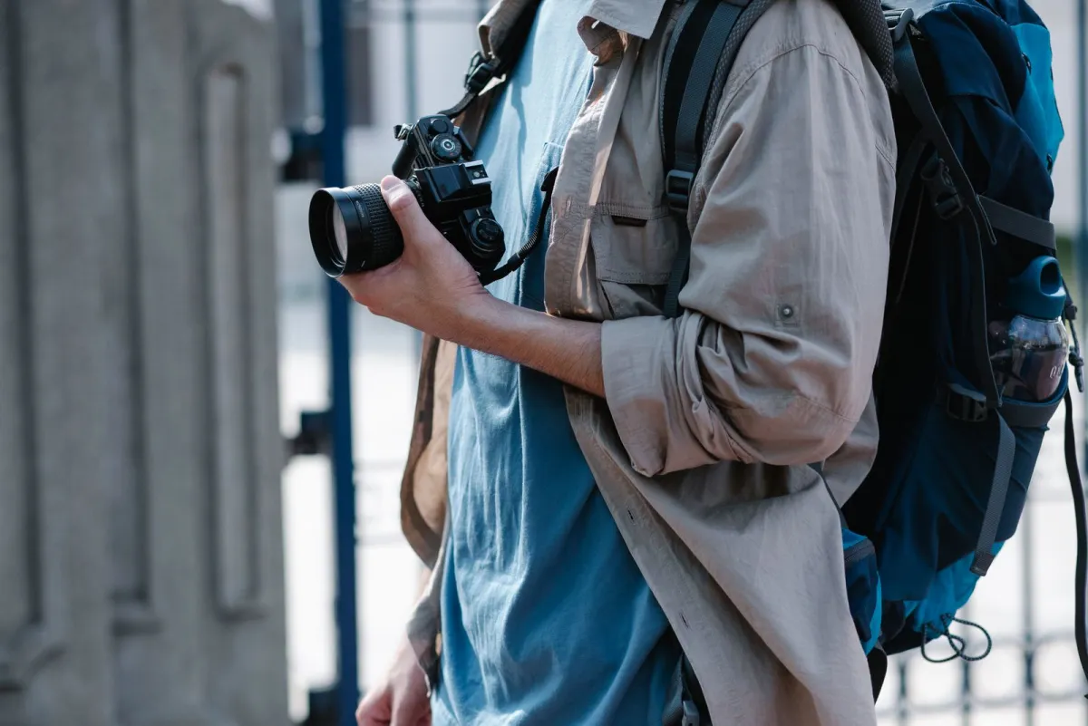 Traveler in a city street carrying a compact backpack with a camera in hand