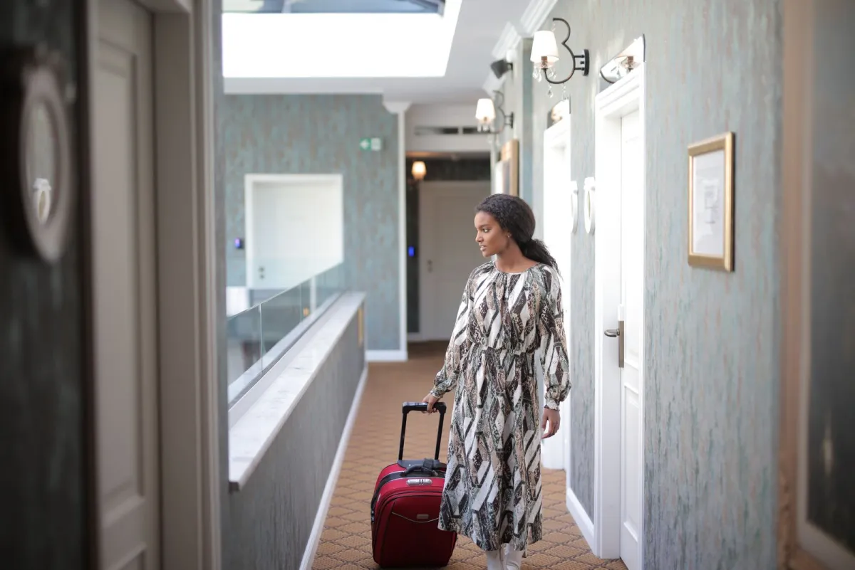 Traveler wheeling a suitcase through a stylish hotel corridor