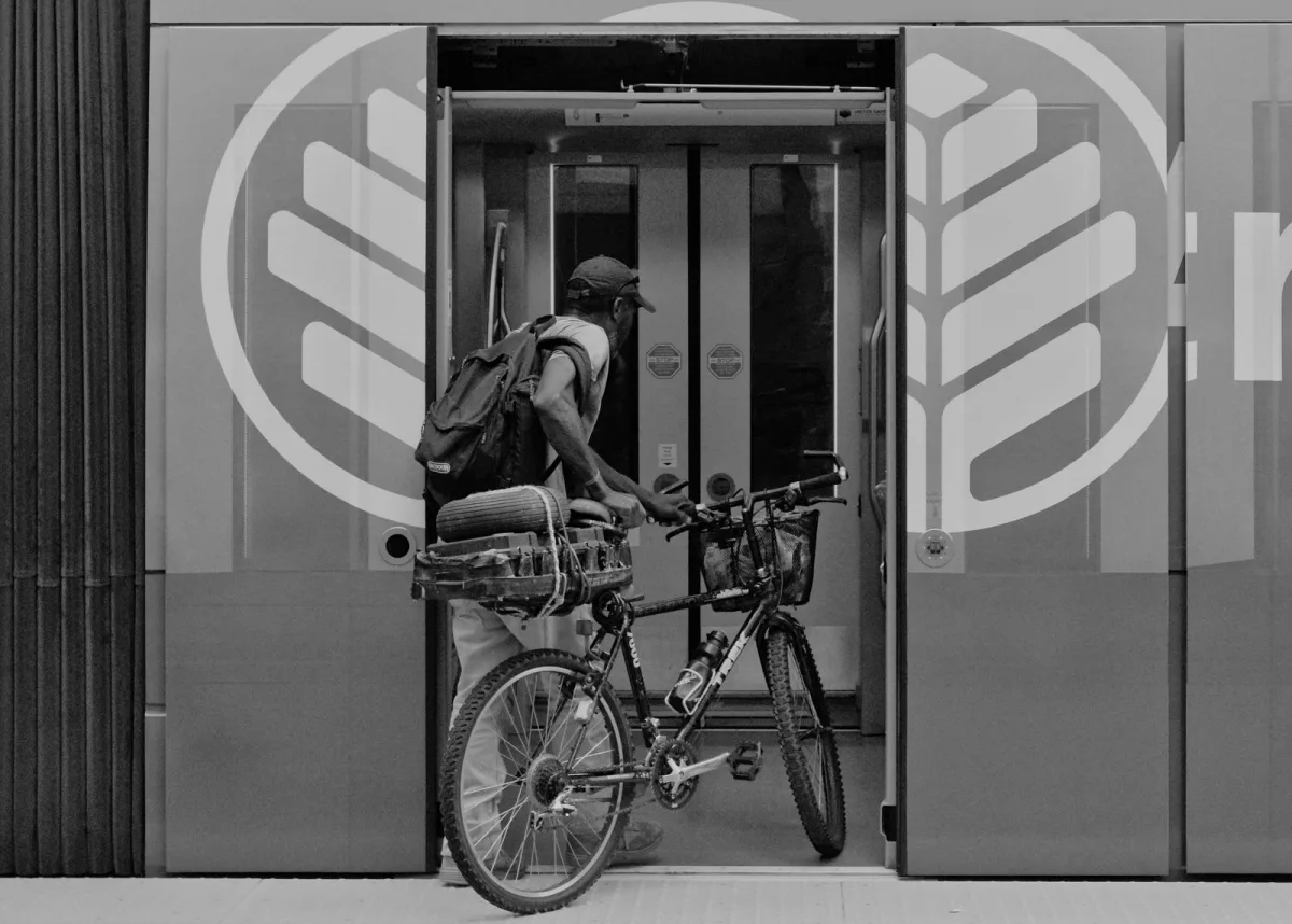 Cyclist wheeling a bike with a backpack into a station