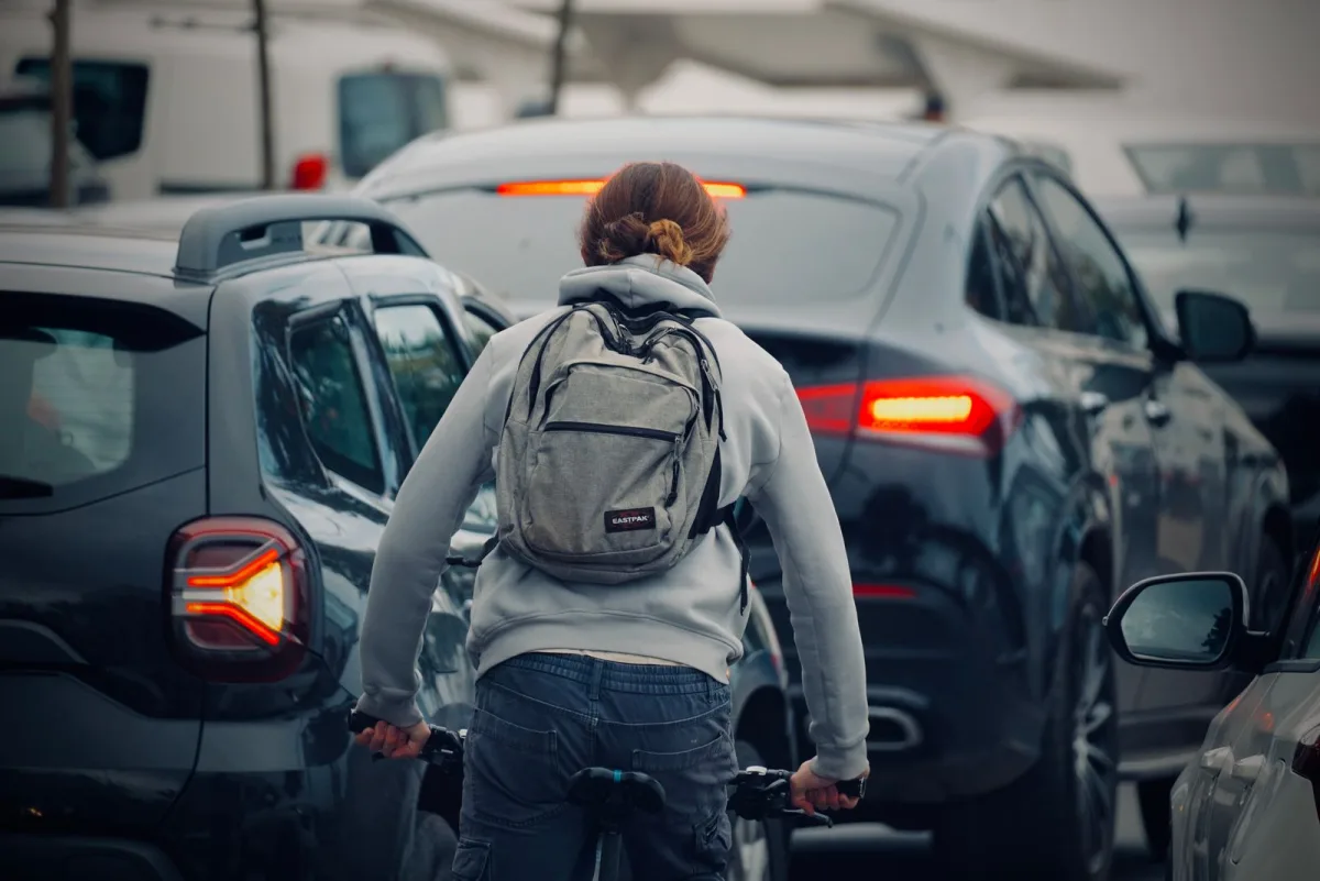 Cyclist with a backpack riding through city traffic