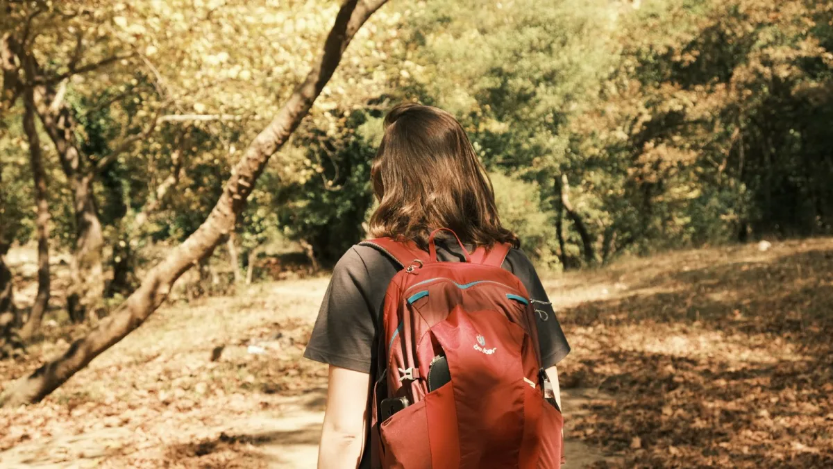 Woman hiking a forest path with a red day pack