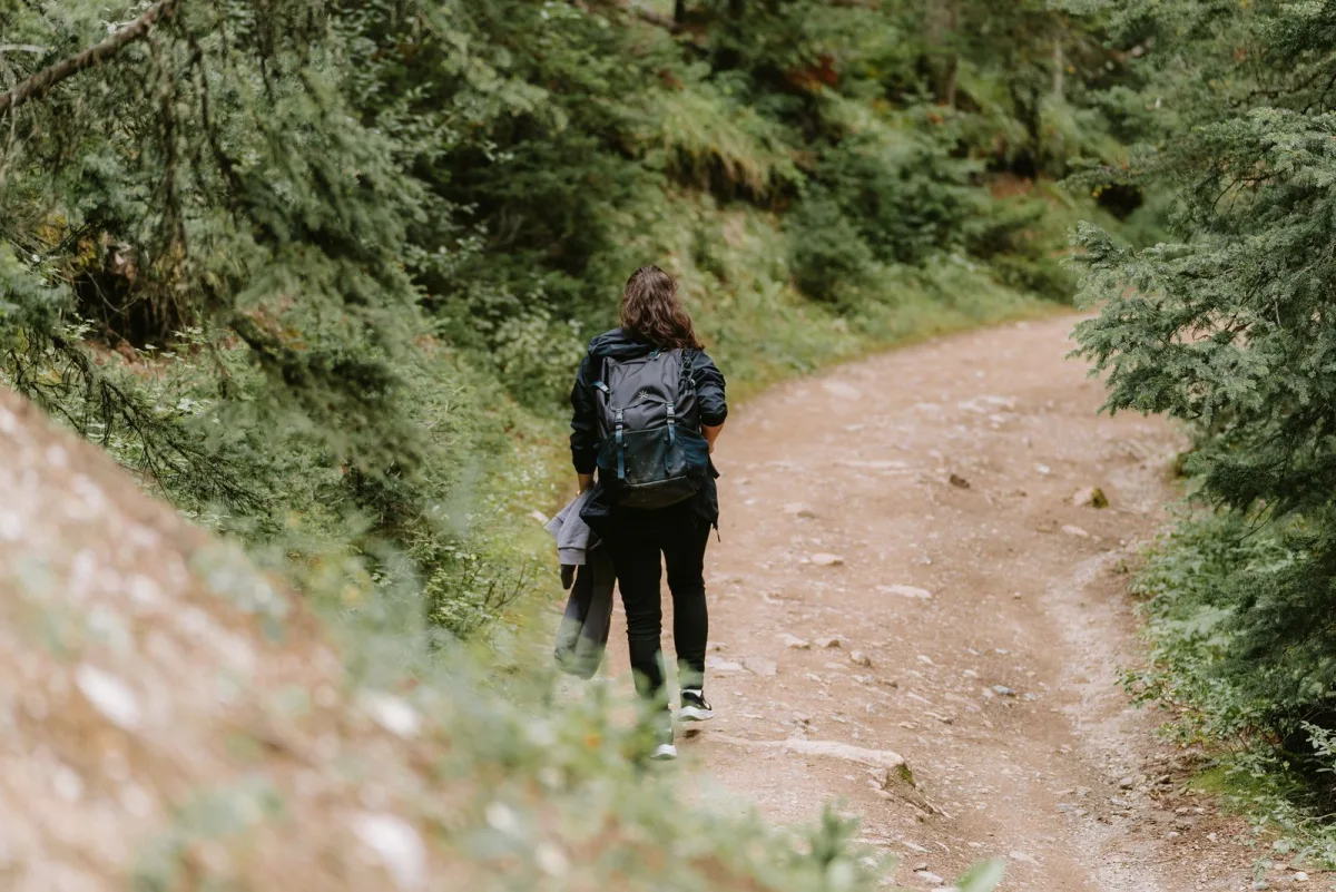 Woman carrying a loaded pack on a wide mountain road