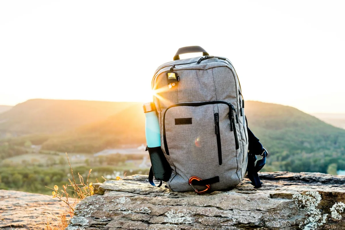 Hiking pack and flask resting on rock at sunset