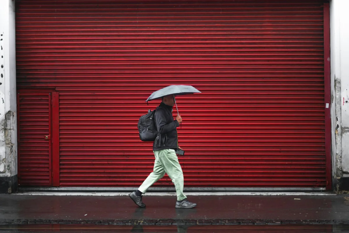 Man with an umbrella and a shoulder bag on a wet pavement