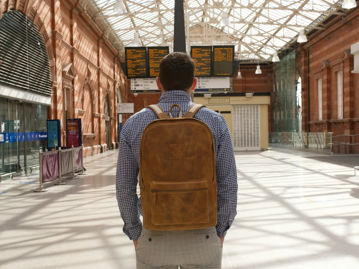 Man carrying a brown and black work backpack on a city sidewalk