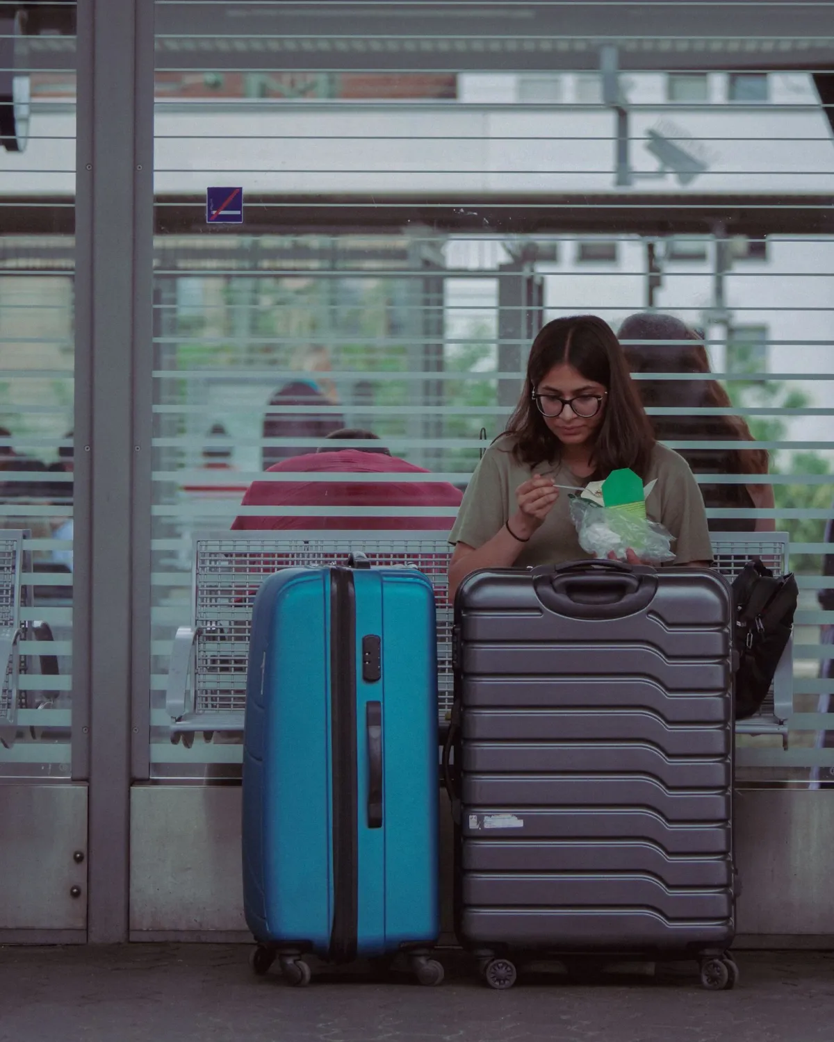 Teal and grey hardside spinner suitcases standing together at a station