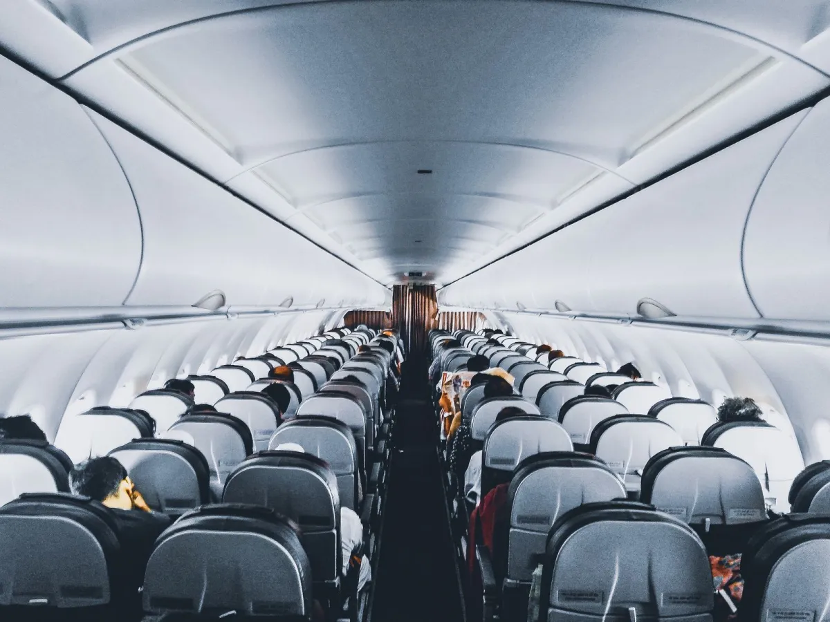 Passengers seated along an airplane cabin aisle after boarding