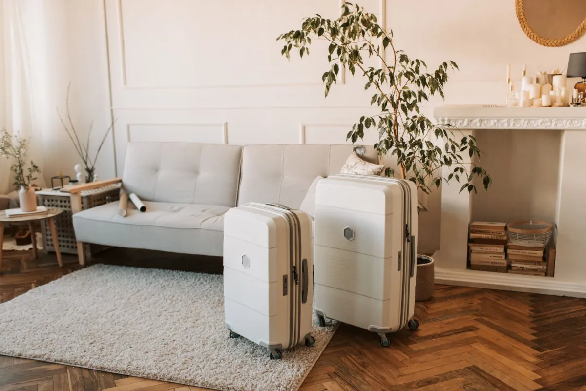 Two white hardside suitcases standing side by side in a living room
