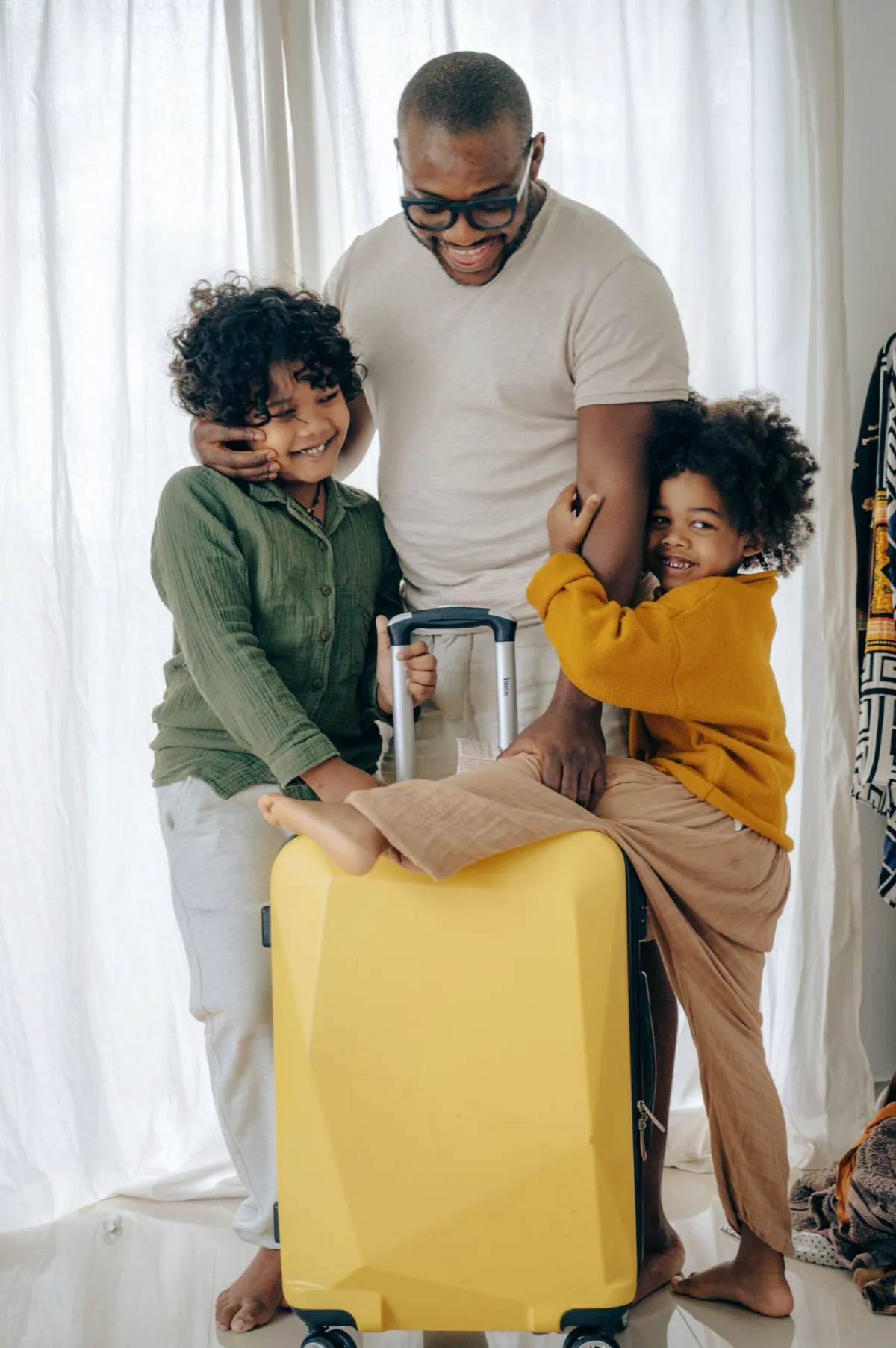 Family with two children standing around a bright yellow hardside suitcase