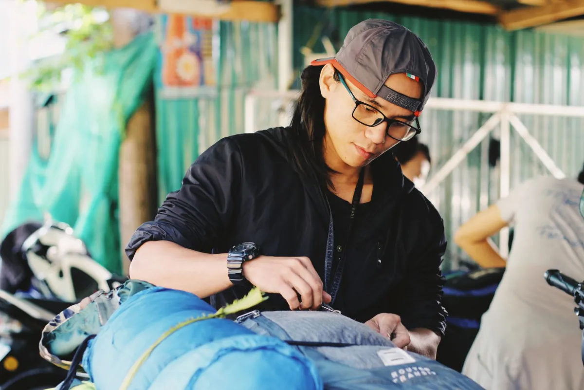 Man packing clothes into an open travel backpack on a table