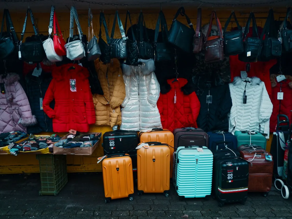 Rolling suitcases lined up at an outdoor market stall