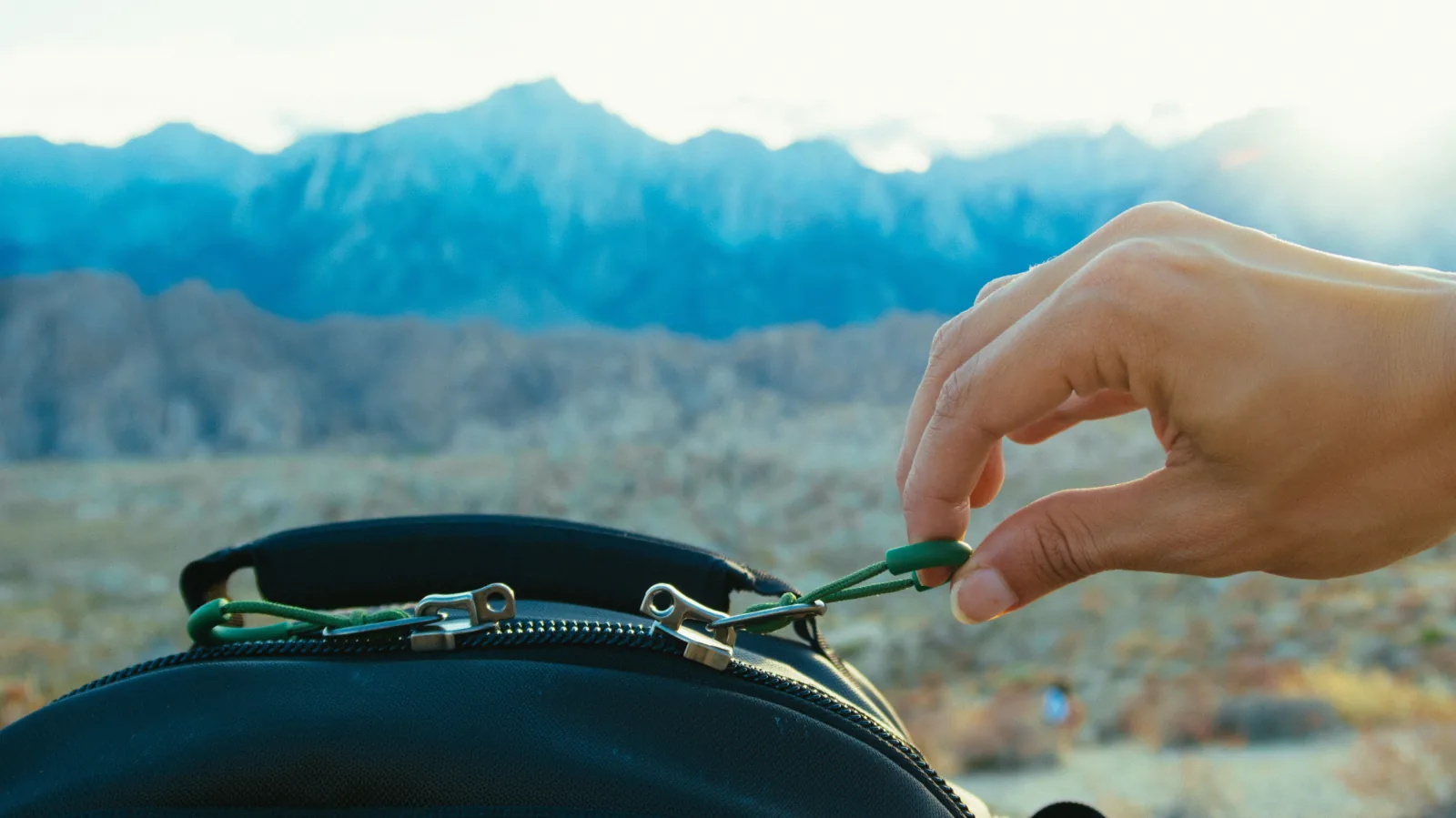 Hand pulling the intact zipper on a black backpack outdoors