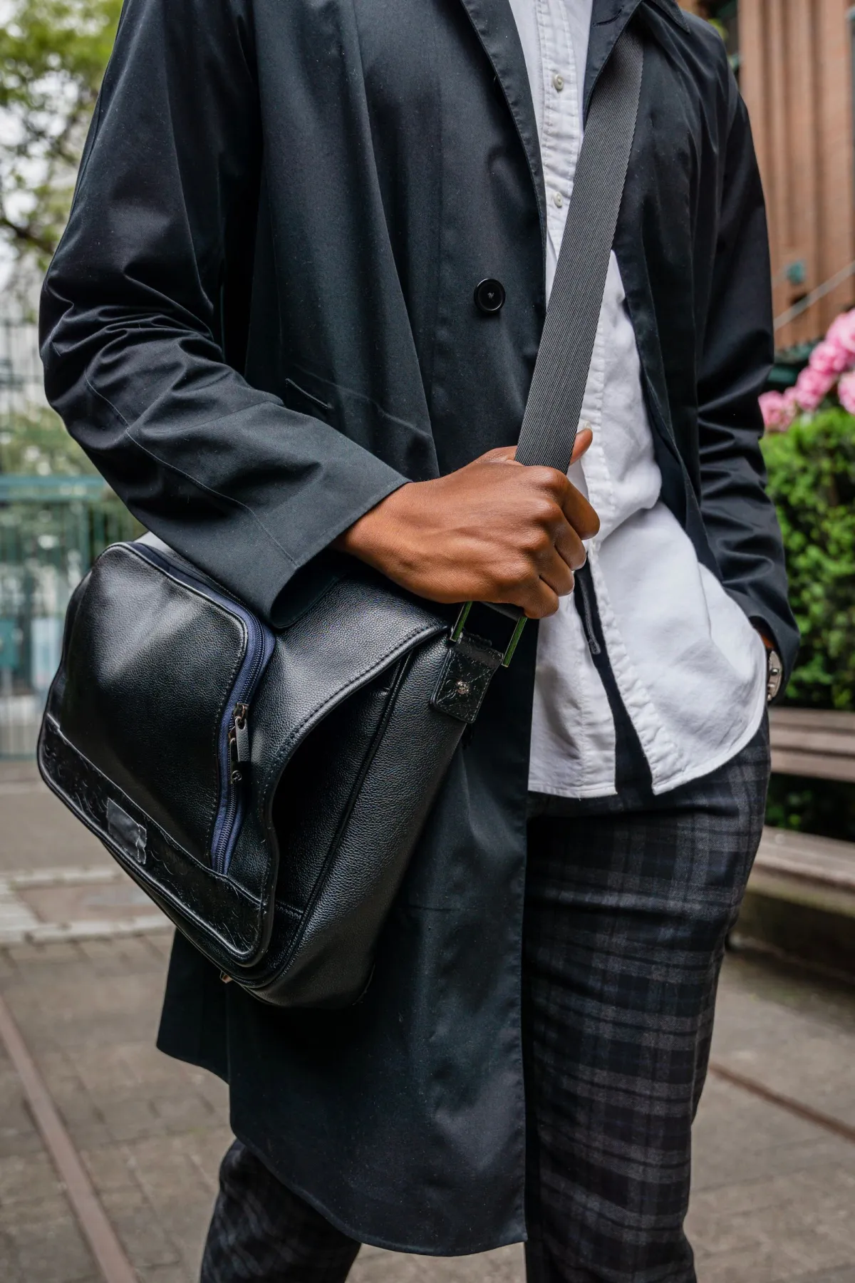 Man carrying a leather sling bag across his chest on a city street